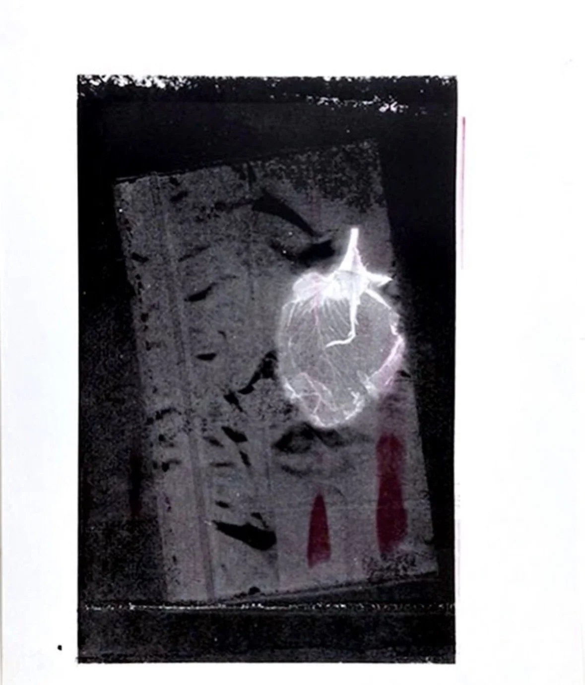 A broken glass with spider web cracks, placed on a surface with scattered debris and three red paint streaks nearby.