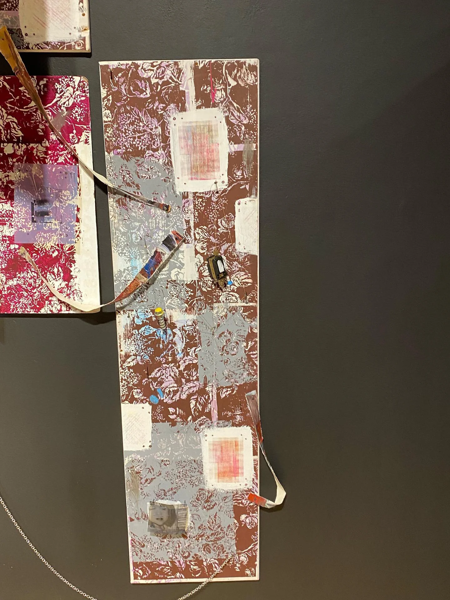 A puzzle with floral and abstract designs, featuring some smaller photos and objects on it, assembled on a black surface.