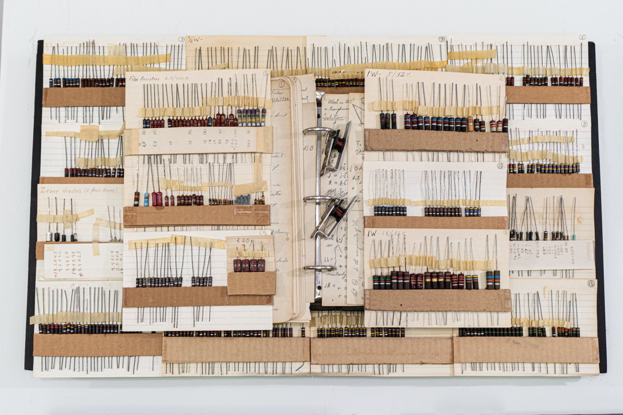 Notebook - Inspired by Elmer’s collection of electronic components. Vintage black notebook, electronic components, tape, cardboard. 14” x 24” x 2”. 2014
