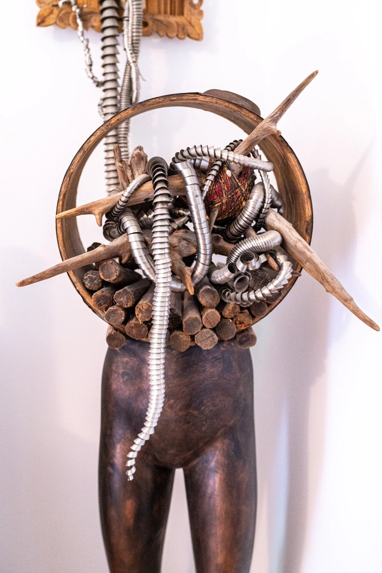 Displaced Person - Self portrait depicting a time of intense ankle pain where I attempted to “Abandon the body - rescue the brain”. Cast self portrait mask, stainless steel coils, brass wings, wood spikes, drift wood, vintage wood barrel, manikin for
