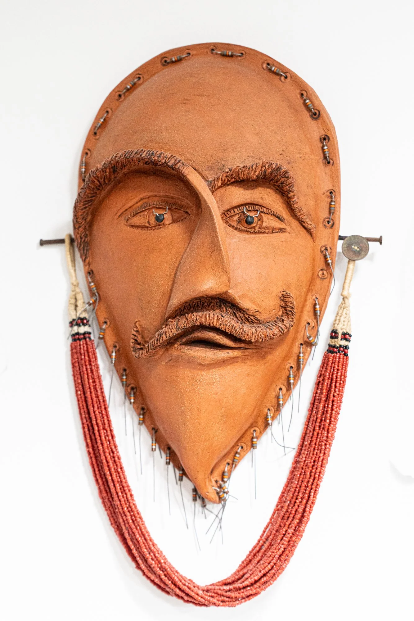 Conquistador Mask - Intuitively modeled. Terra cotta  clay, beads, horseshoe nails, beaded necklace. 16” x 9” x 3” 