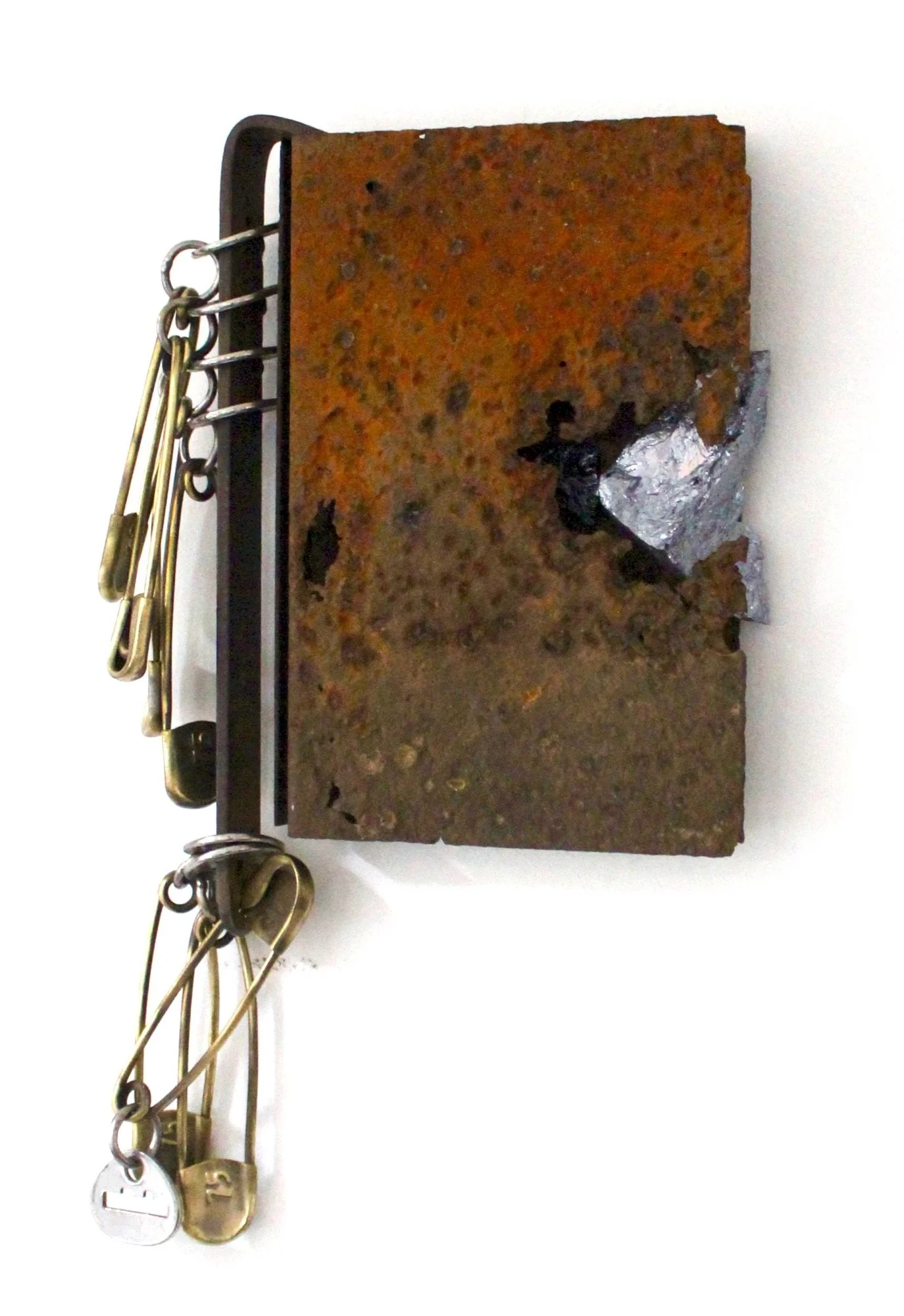 Conjure - Inspired by the idea that books, and  photographs often bring to mind memories that are forever attached to us. Brass safety pin, rusty steel, silica ore, steel. 14.5” x 9” x 1.5”. 2014 (in a private collection)