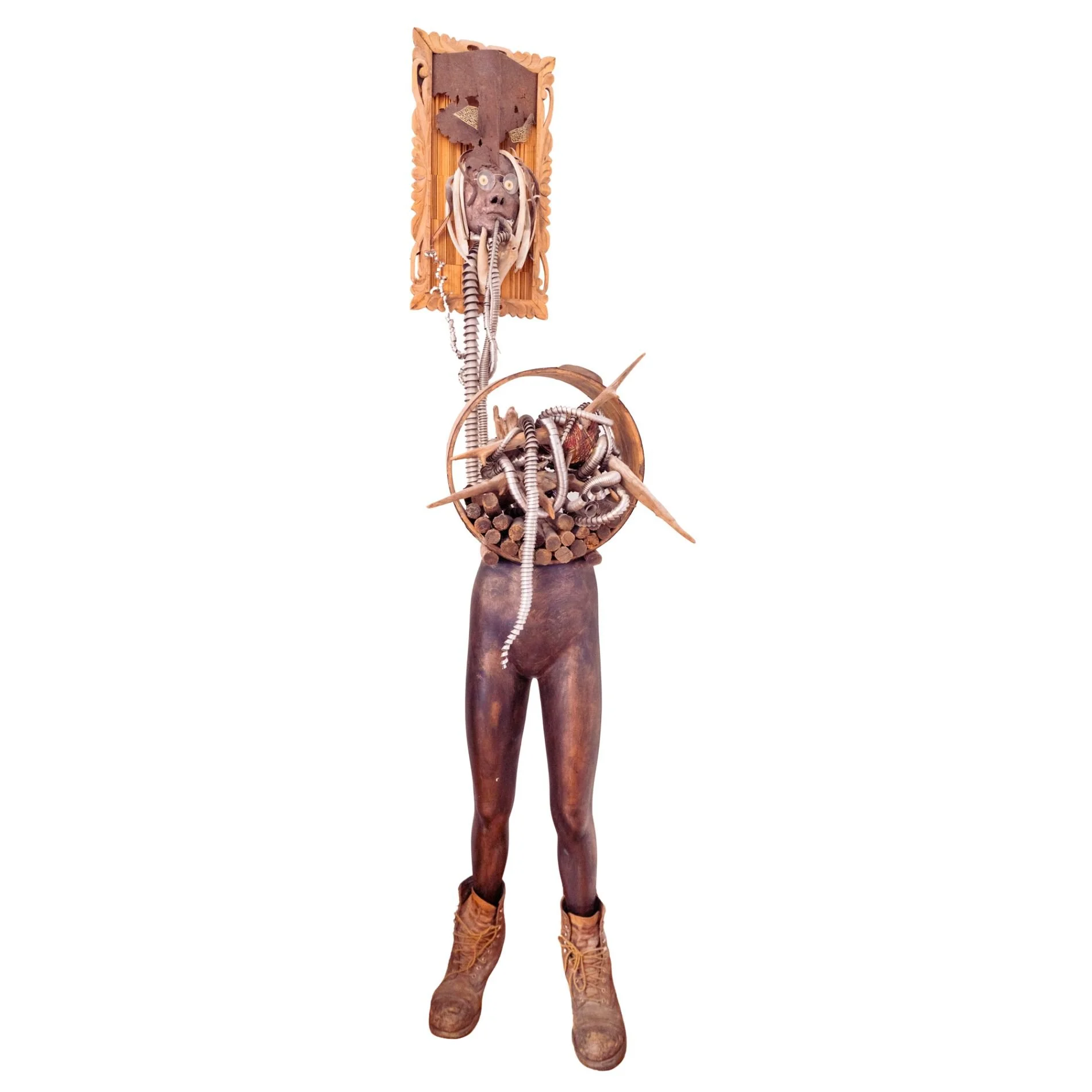 Displaced Person - Self portrait depicting a time of intense ankle pain where I attempted to “Abandon the body - rescue the brain”. Cast self portrait mask, stainless steel coils, wood spikes, drift wood, vintage wood barrel, manikin form, steel toe 