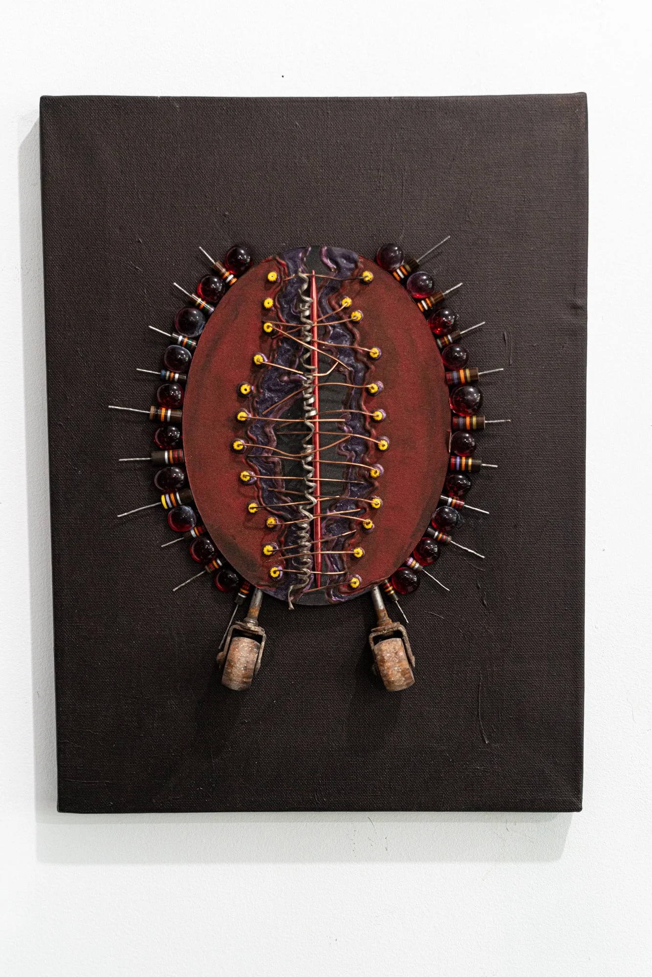 Wheelie - Inspired by the antics of watching kids ride bikes. Electrical resistors, beads, wire, red gems, crochet hook, wooden wheels, painted matt board. 16” x 12” x 2”. 2010