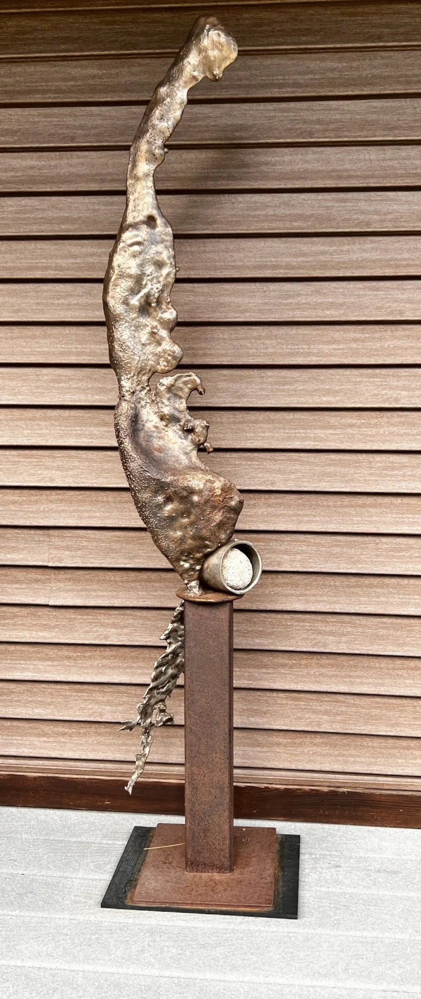 Freeze Flow - This sculpture explores the dynamic contrast between the implied, organic flow of molten steel and rigid, geometric forms. A river rock is incorporated to accentuate this visual dialogue. Cast stainless & mild steel, rock. 71” x 15” x 1