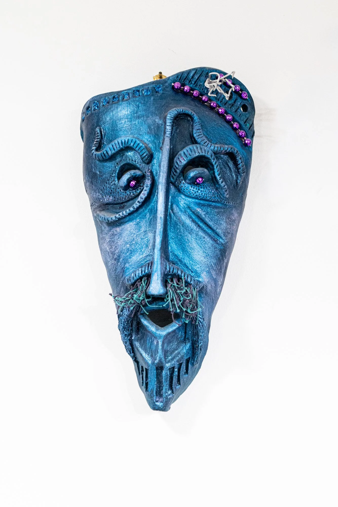 Blue Mood Mask (Purple Beads) - Intuitively modeled. Low fire clay painted and adorned with purple beads and aluminum wire.  13” x 6” x 3” 