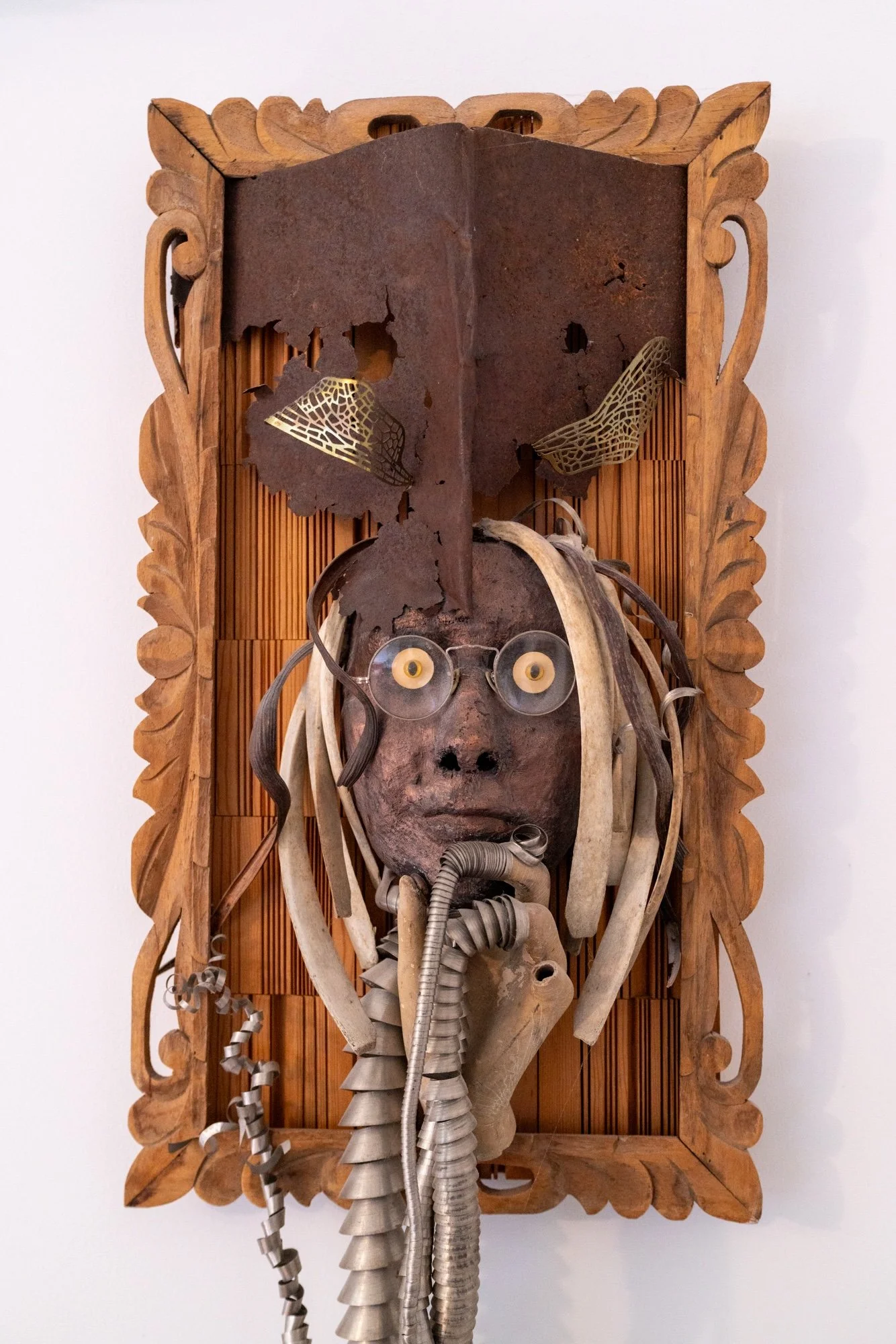 Displaced Person - Self portrait depicting a time of intense ankle pain where I attempted to “Abandon the body - rescue the brain”. Cast self portrait mask, stainless steel coils, wood spikes, drift wood, vintage wood barrel, manikin form, steel toe 
