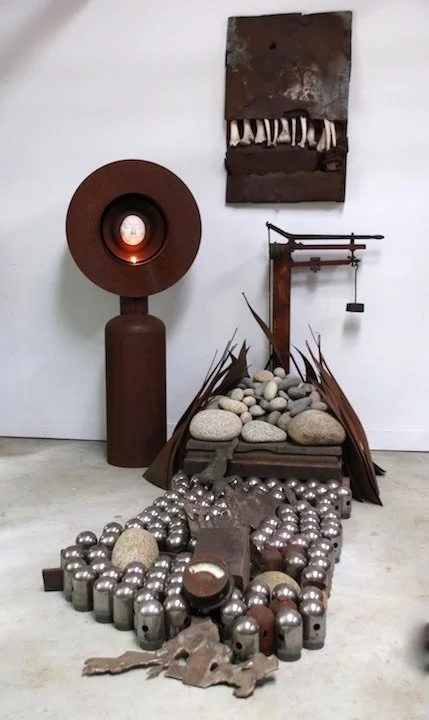 Heavy Laden - Inspired by the pandemic of 2019 and the overarching fear and anxiety of that time period. Yet to be publicly displayed. Self - portrait with flame monument, vintage scale, wall sculpture with bones, rocks, steel, cylinder caps, cast st