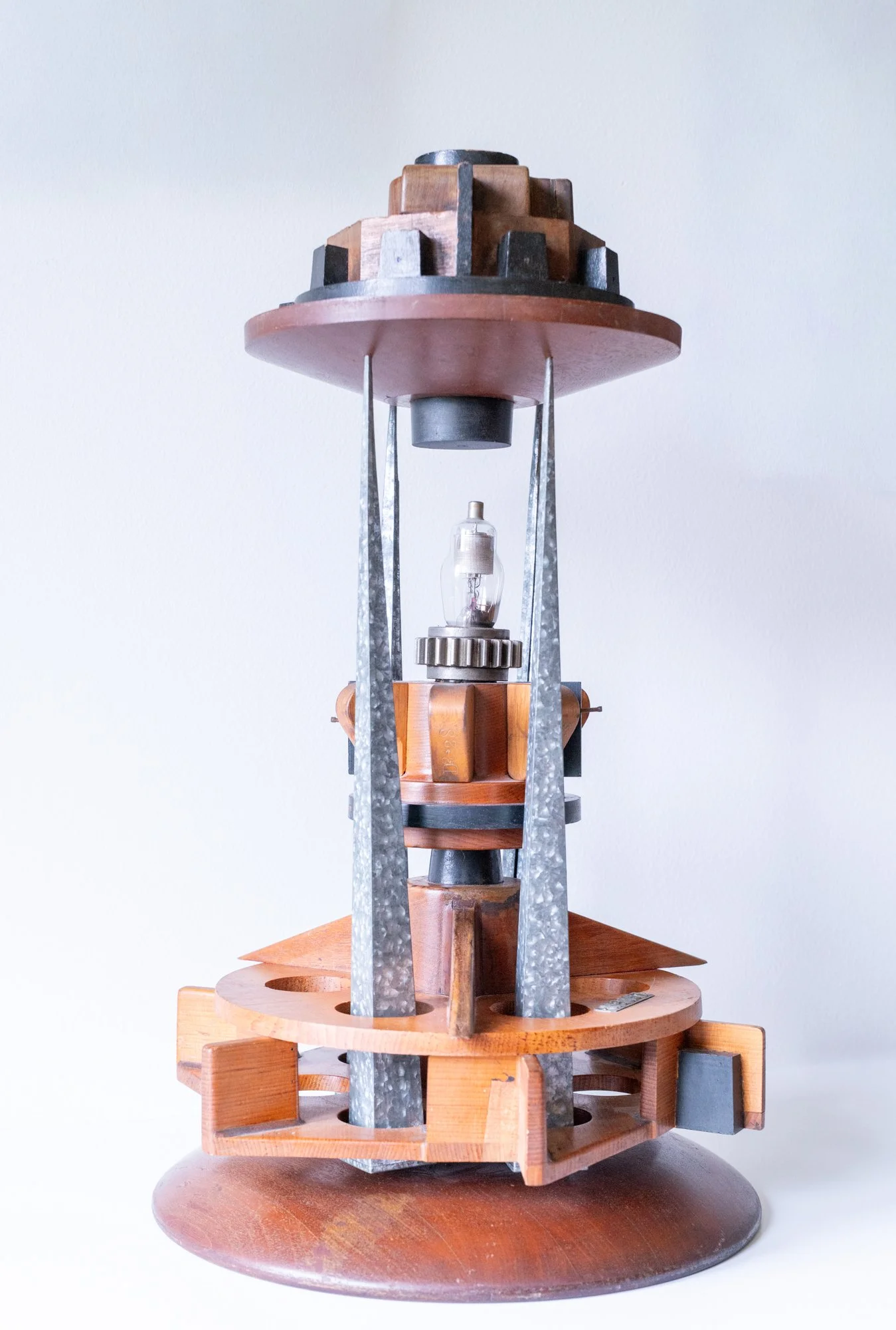 Beacon - Inspired by that which guides, encourages or inspires. Wood pattern pieces, galvanized candle forms, light bulb, gear. 25” 14.75” x  14.75”. 2020-21