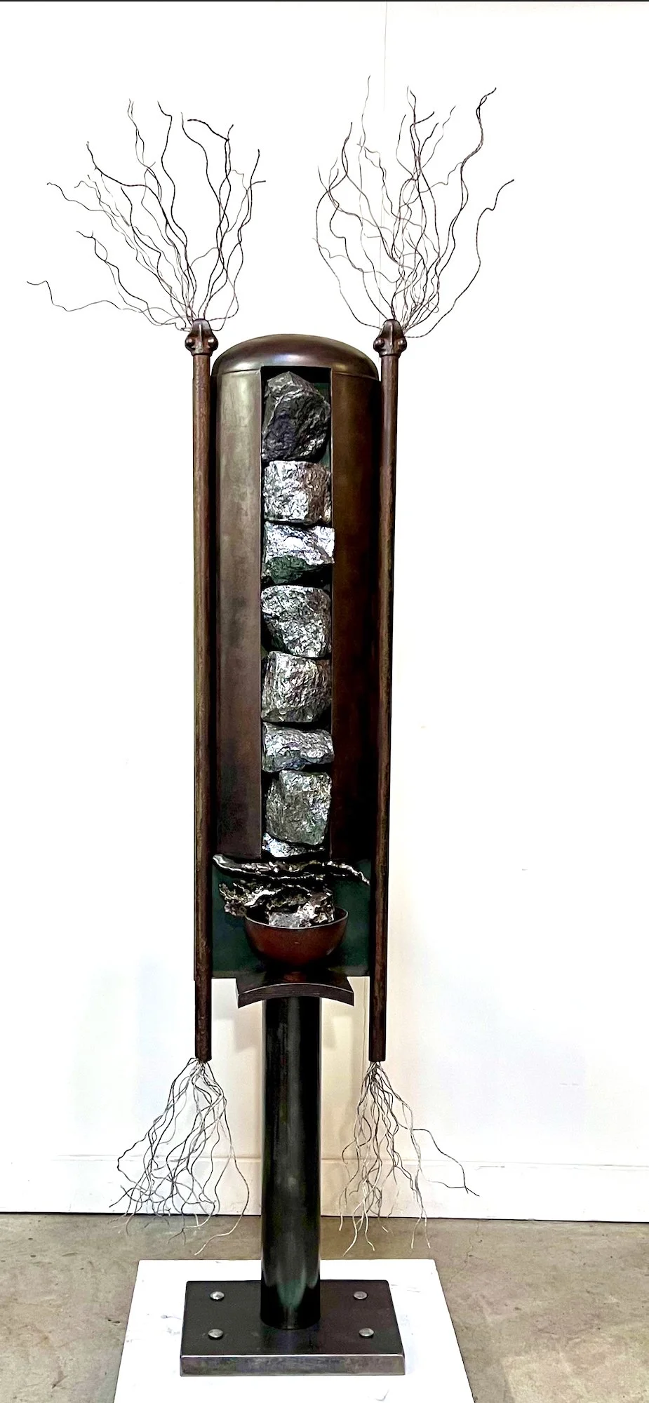 Dispenser - Inspired by earth’s natural resource, Silica ore and the effect mining for natural resources has on the environment. Welded steel, deconstructed propane tank, cow stanchion posts, cast stainless steel, aluminum wire, silica ore. 76” x 16”