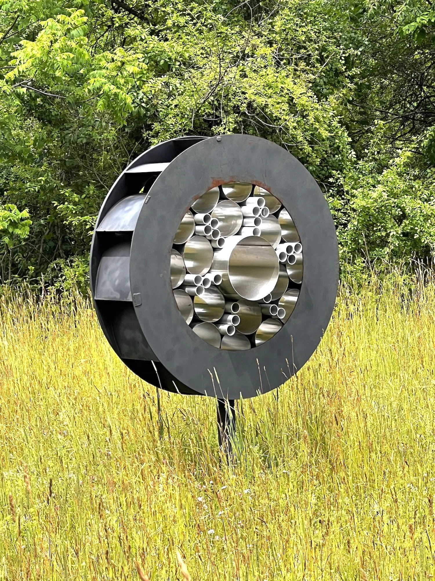 Surveillance - Inspired by the prevalence of monitoring methods that are part of our daily lives. As one drives by this piece, it appears to flicker like it’s taking a photo. Welded steel, stainless steel and aluminum cylinders. 7’5” x 5’ x 30.50”. 2