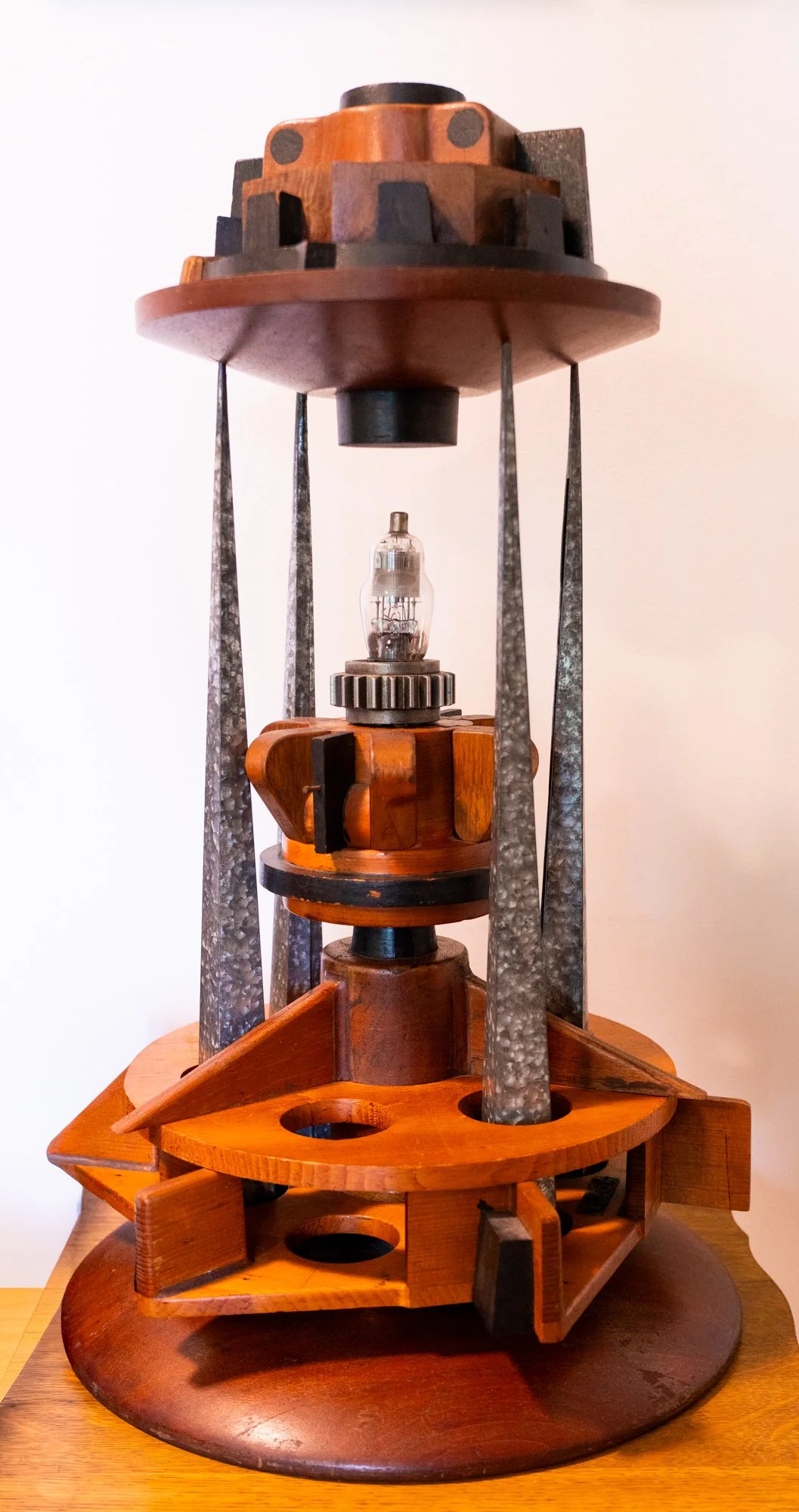 Beacon - Inspired by that which guides, encourages or inspires. Wood pattern pieces, galvanized candle forms, light bulb, gear. 25” 14.75” x  14.75”. 2020-21