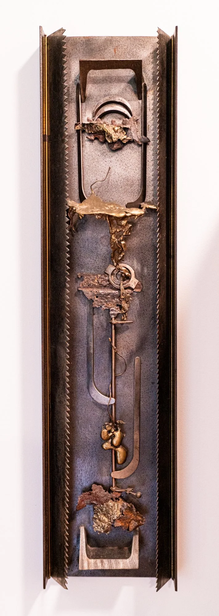 Allegory - Inspired by telling a story by layering unique objects in a vertical format indicating sky, earth and underground. Saw blades, bronze, steel, miscellaneous steel objects. 29’ x 7” x 4.” 1989 