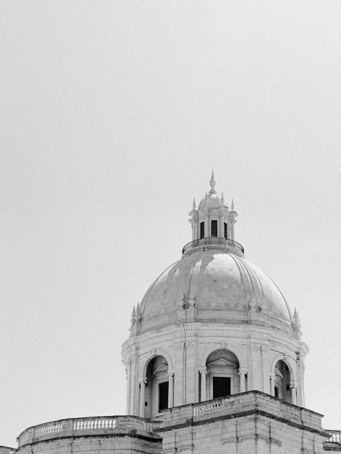 Black and white image of a historic dome with architectural details, against a clear sky.