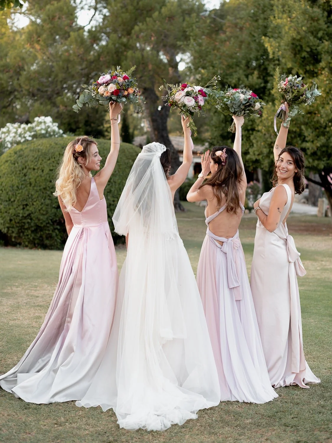 Bride and bridesmaids holding bouquets, back view outdoors