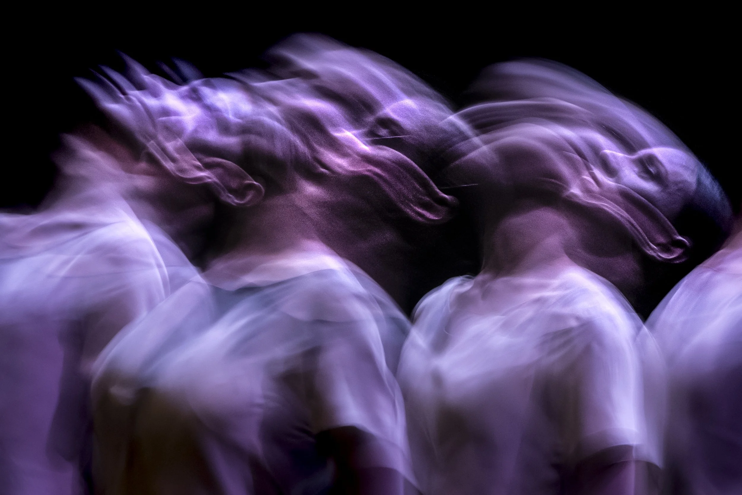 Abstract image of purple and white light streaks against a black background.