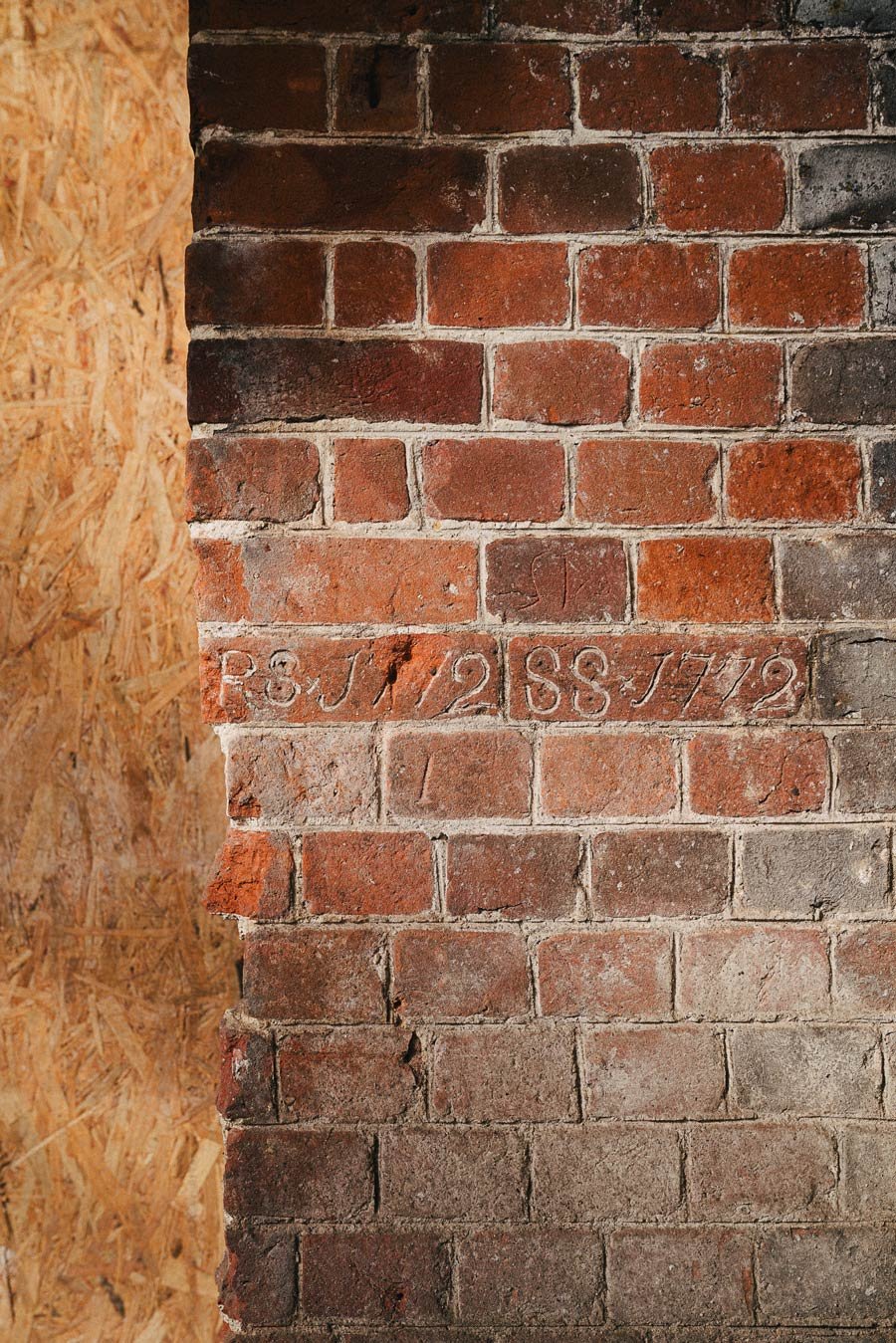 Close-up of a brick wall with the engraved text "R.G.I. 12 SS J 79".