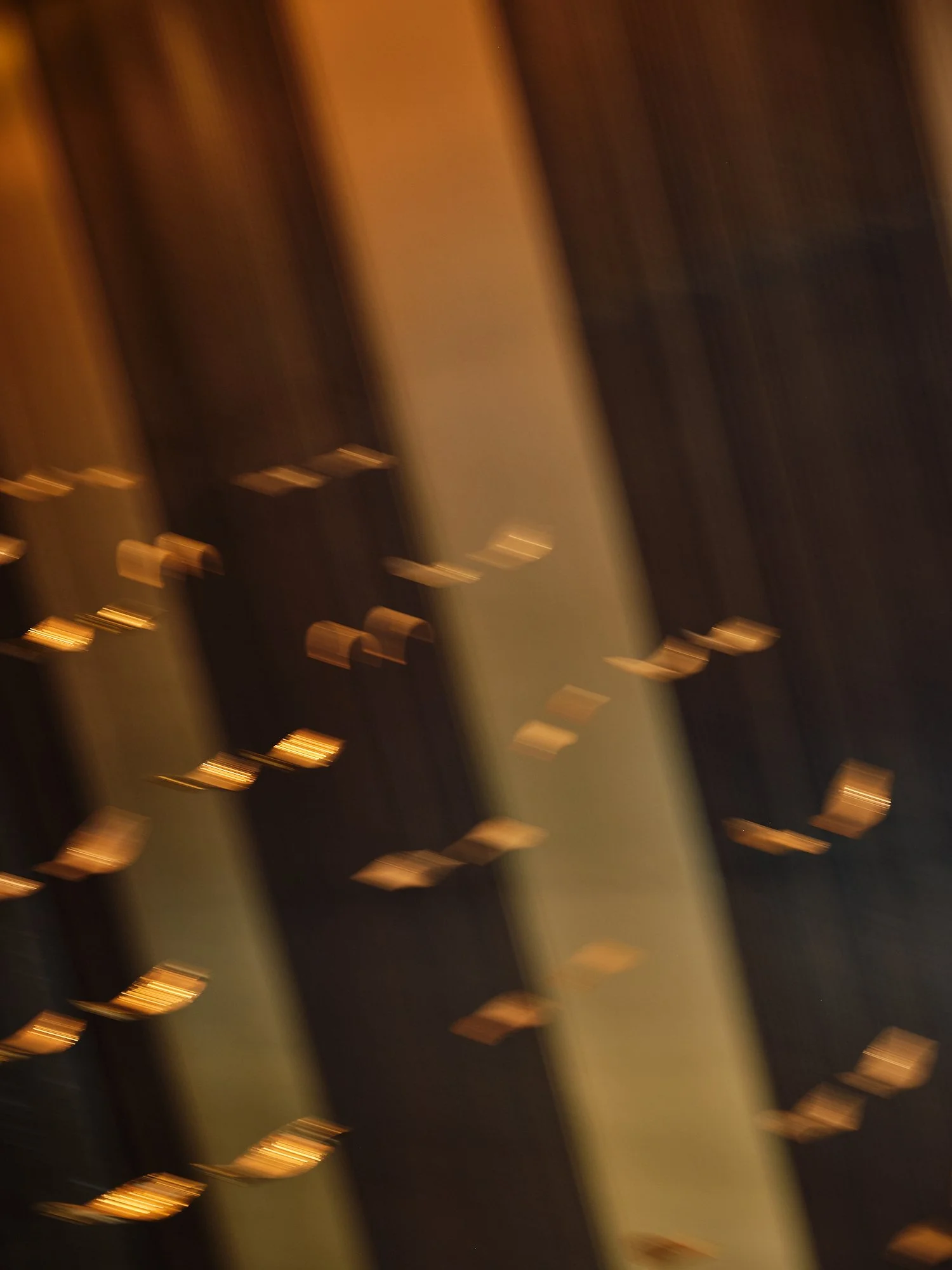 Blurred image showing a surface with multiple gold-colored objects arranged on it, possibly metallic or jewelry items, with a dark background.