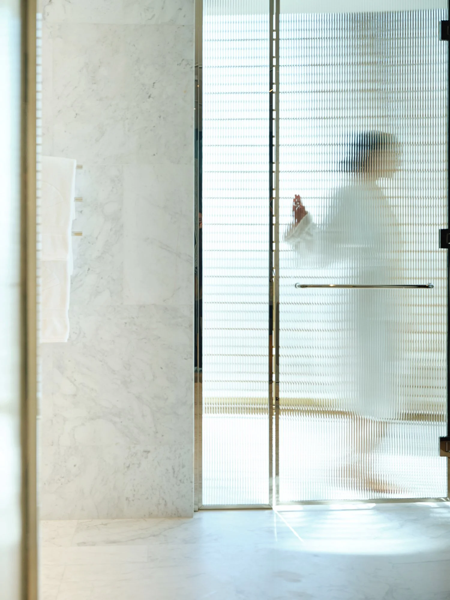 Person inside an elevator viewed through a textured glass door.