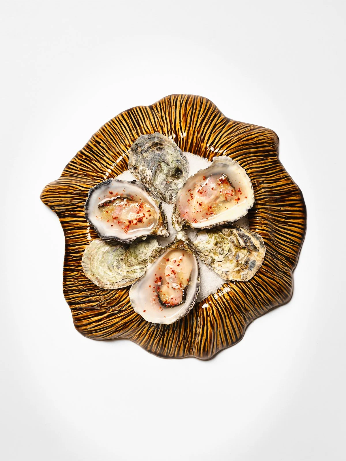 A decorative plate with scalloped edges, containing open oysters on a bed of ice.