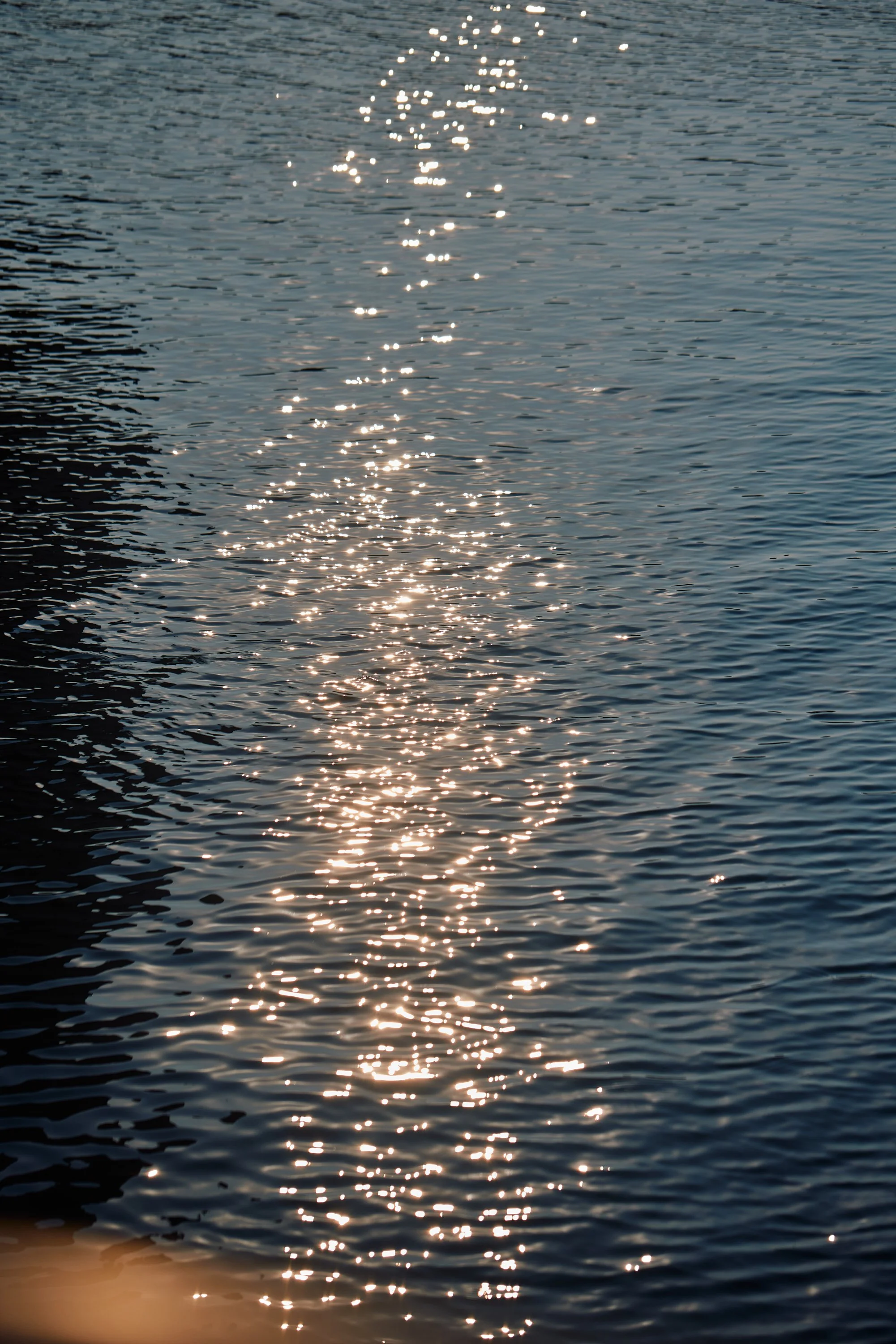 Sunlight reflecting off a calm body of water, creating a sparkling, shimmering effect.