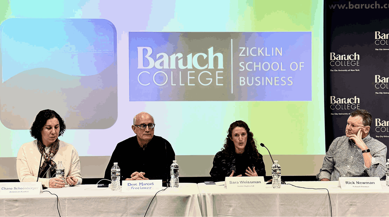 Four people sitting at a table with microphones and water bottles during a panel discussion at an event. Behind them, a large presentation screen displays the text "MaKi Media Conference NYC December 2024" and logos for Baruch College and Zicklin School of Business.