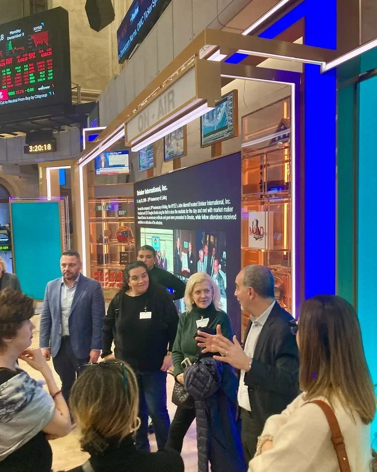 Group of people, including a man in a police uniform, engaging in a discussion at an event or conference in a building with digital screens and colorful lighting.