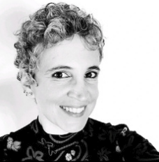 Black and white photo of a woman with curly hair smiling at the camera.