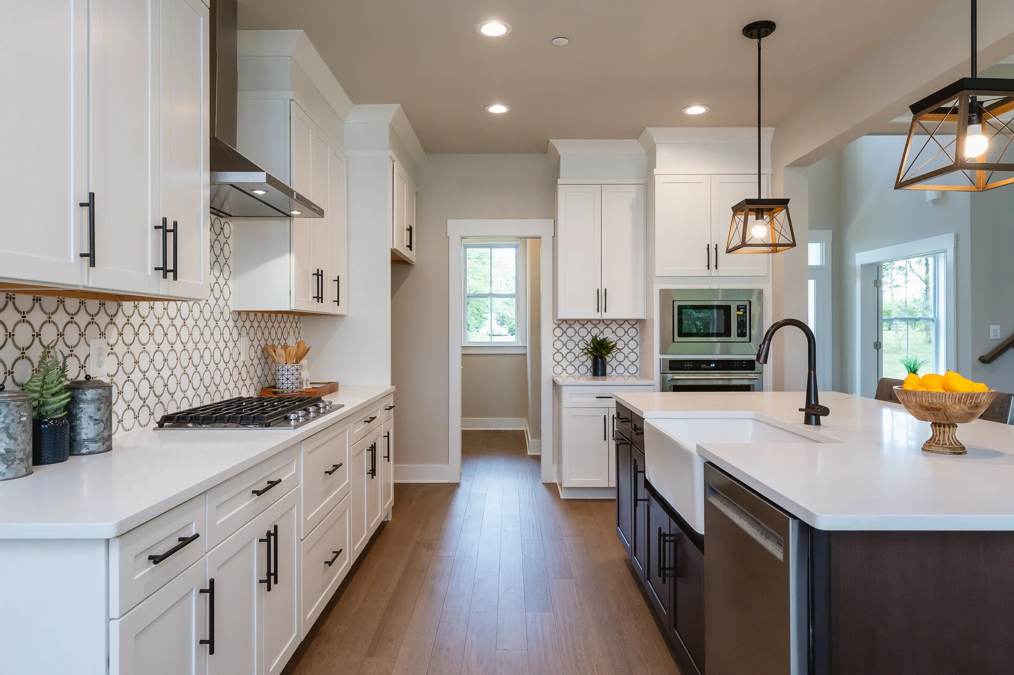 Modern kitchen with white cabinets, a kitchen island, a gas cooktop, pendant lighting, and a window view of the outdoors.