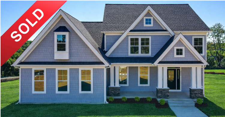 Newly sold two-story house with gray exterior, multiple gabled roofs, large windows, and front porch on green lawn.