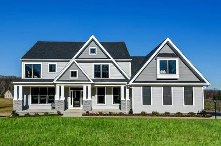 Modern two-story house with white siding, black roof, stone accents, and multiple windows, set on a well-maintained lawn under a clear blue sky.
