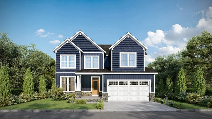 A two-story house with blue siding, white trim, and a front porch with a wooden door. The house has a two-car garage on the right and is surrounded by green trees and shrubs under a partly cloudy sky.