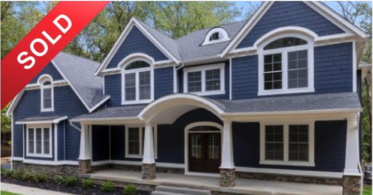 Large blue two-story house with white trim, stone accents at the base, front porch, and multiple windows, with a 'Sold' banner in the top left corner.