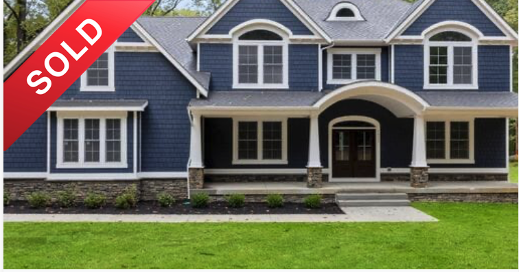 Front view of a two-story blue house with white trim and a covered porch, marked as sold.