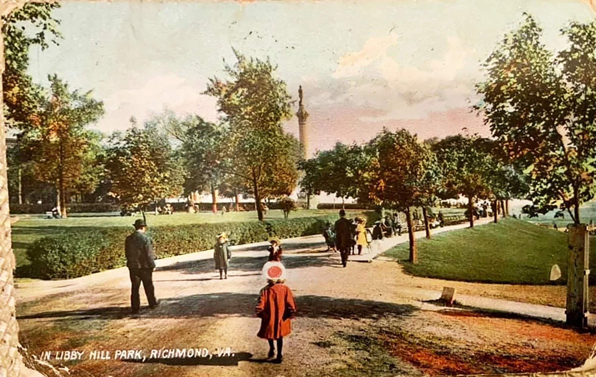 A vintage photograph of Libby Hill Park in Richmond, Virginia, with people walking along a paved path, surrounded by trees and grass, and the Robert E. Lee Monument visible in the background.
