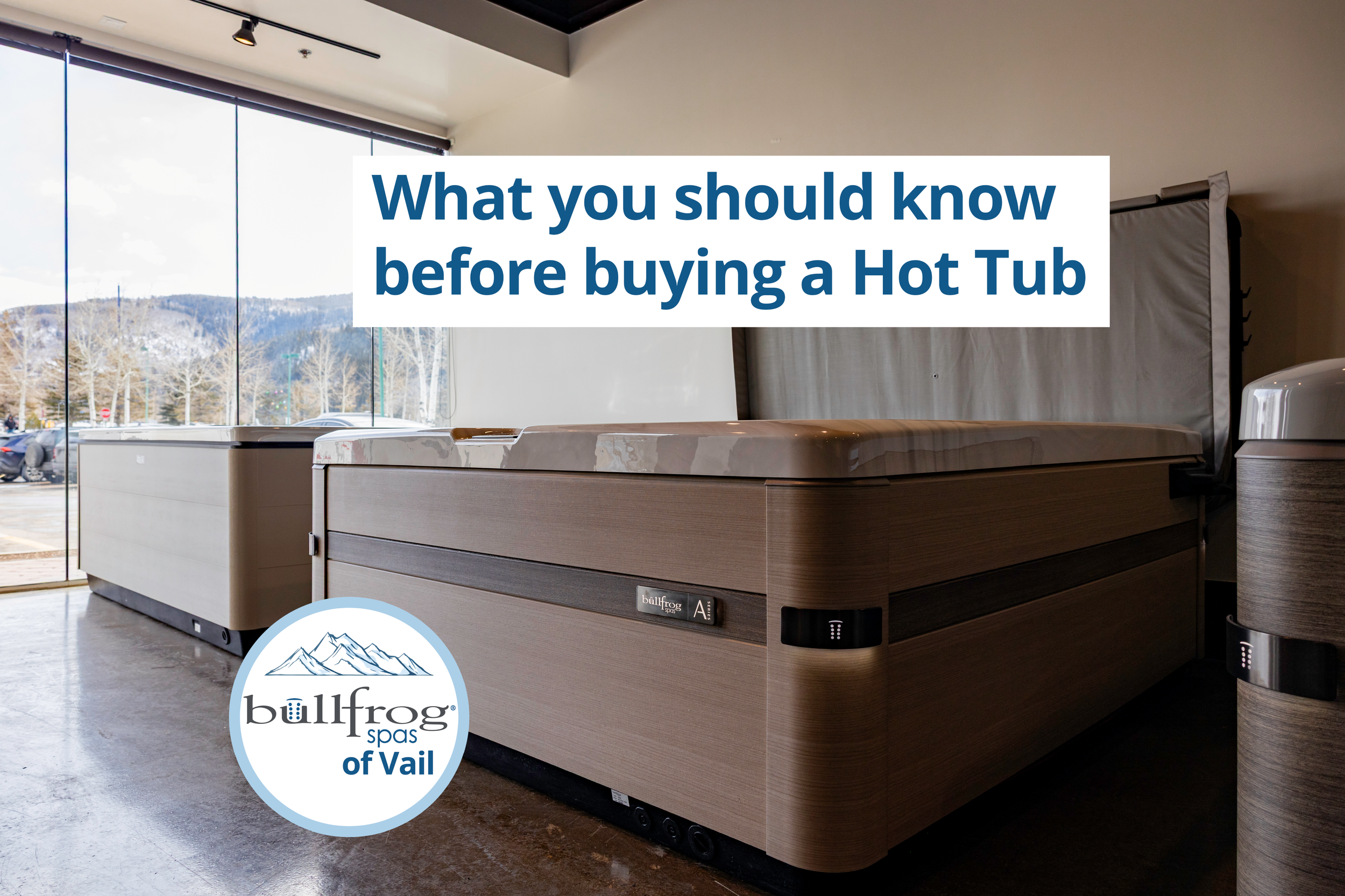 Interior of a showroom with a hot tub in front of large windows showing a parking lot and mountains outside, with text overlay that reads 'What you should know before buying a Hot Tub' and the Bullfrog Spas of Vail logo.