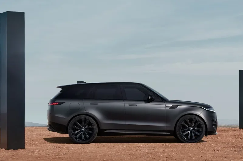 Right-side-profile-shot-of-a-2025-Range-Rover-Sport-Dynamic-SE-with-Stealth-Pack-parked-on-desert-sand-between-two-black-monoliths.jpg.webp