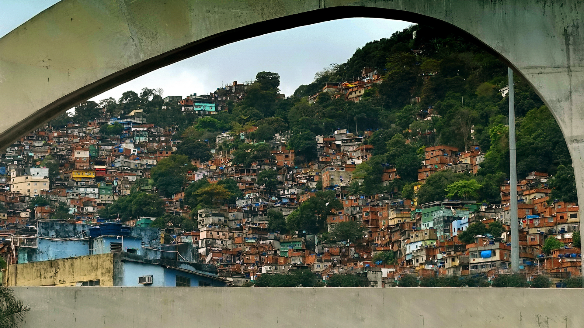 View of hillside shantytown with densely packed houses of various colors seen through a concrete arch.