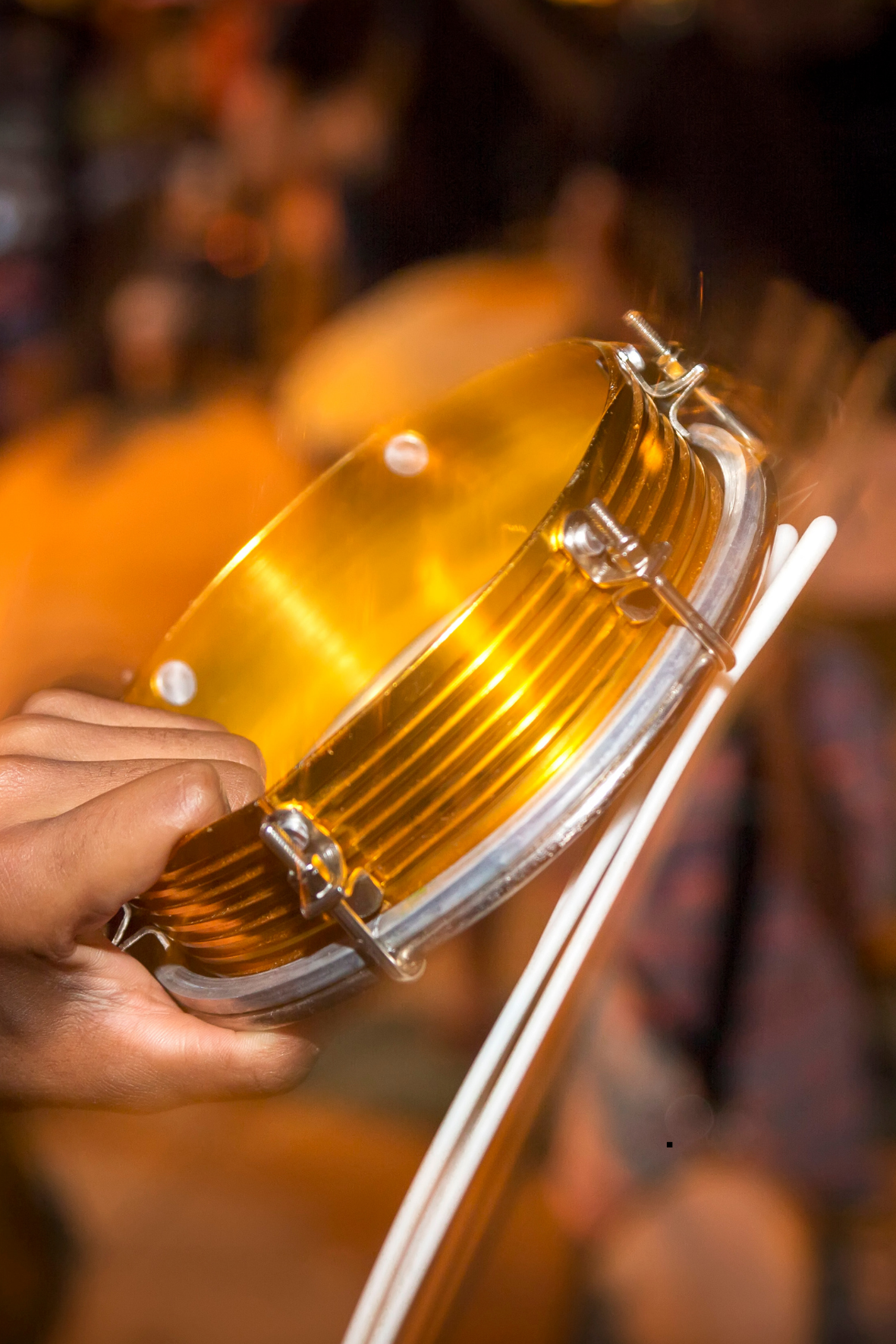 Close-up of a hand holding a lit flame tube with a clear, segmented divider, possibly part of a traditional lantern or decorative light fixture.