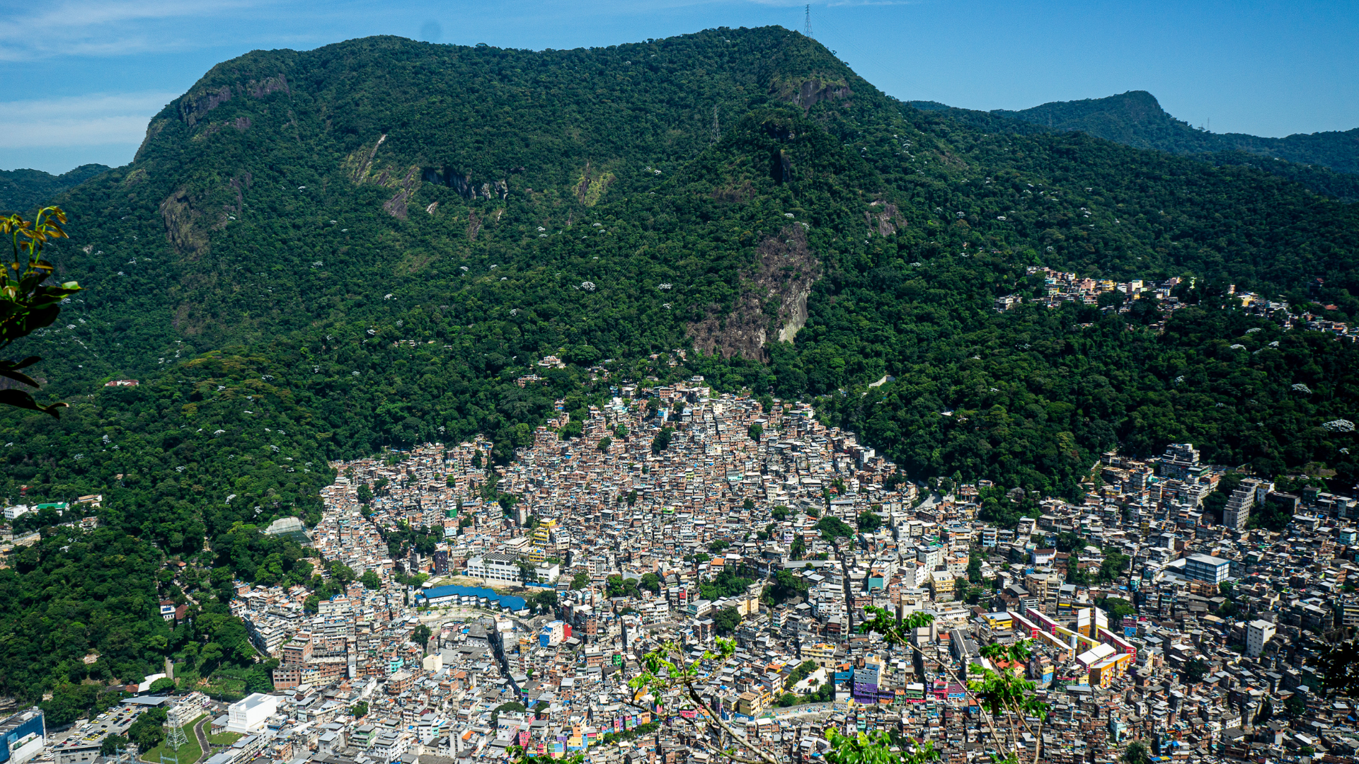 A city nestled in a valley surrounded by lush green mountains, with dense urban buildings and residential areas.