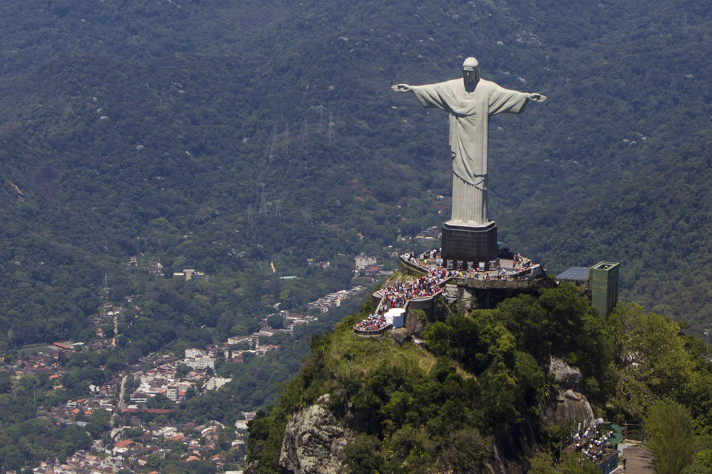 View of the Christ the Redeemer statue atop Corcovado Mountain overlooking Rio de Janeiro, with visitors on the observation platform.
