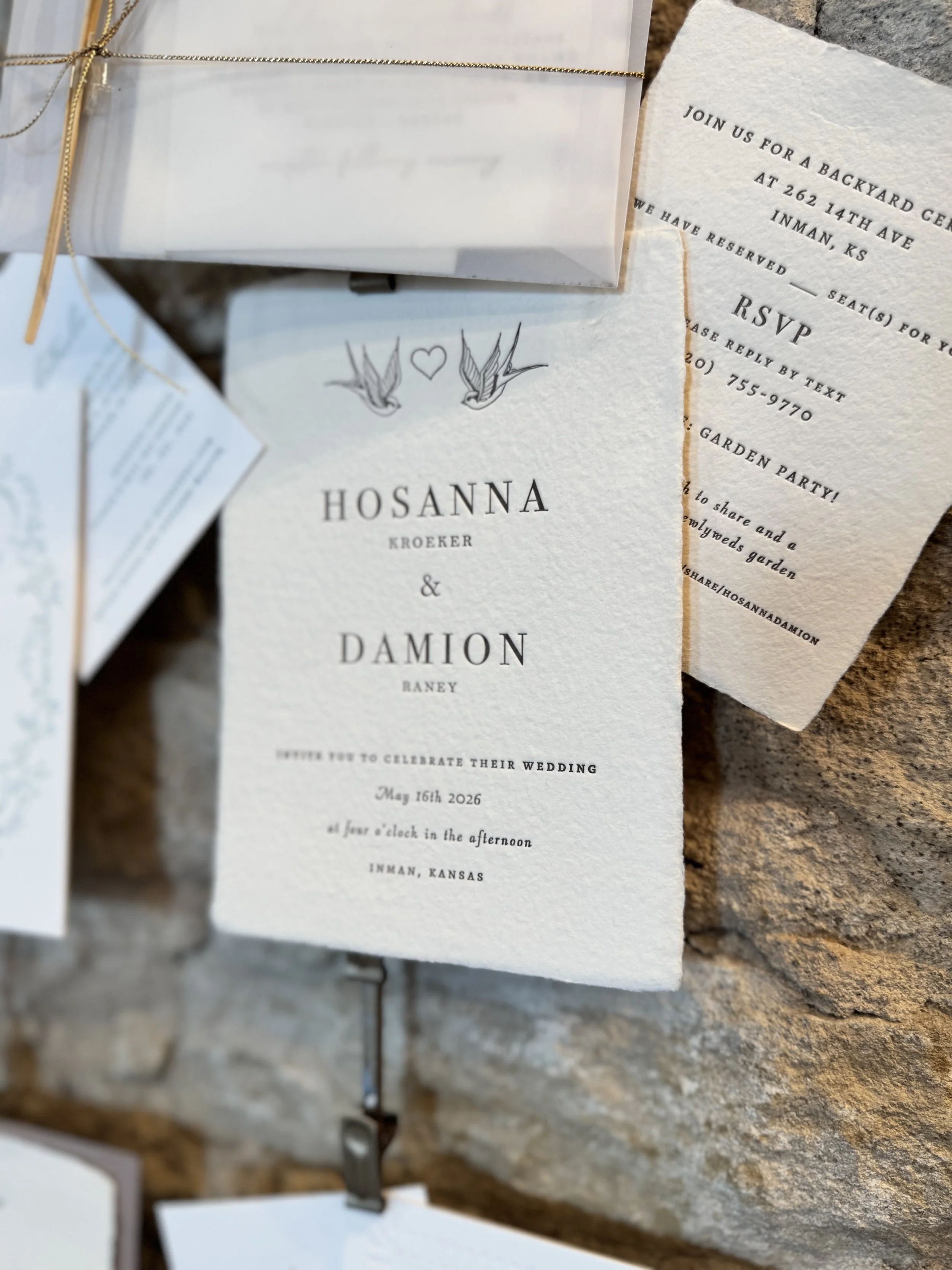 Wedding invitation card with names Hosanna Kroeker and Damion Raney, with a date of May 16th, 2026, and details for a backyard garden wedding in Inman, Kansas.