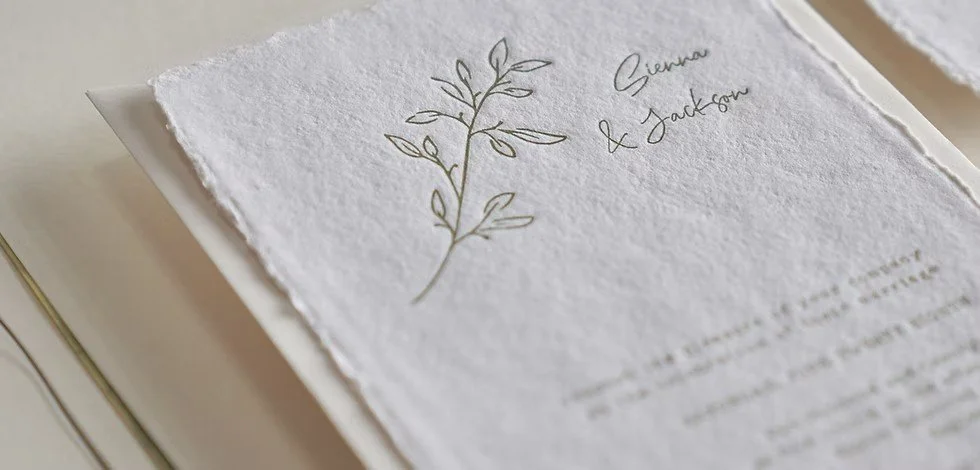 A wedding invitation with elegant gold foil accents, featuring a delicate botanical illustration and calligraphy text.