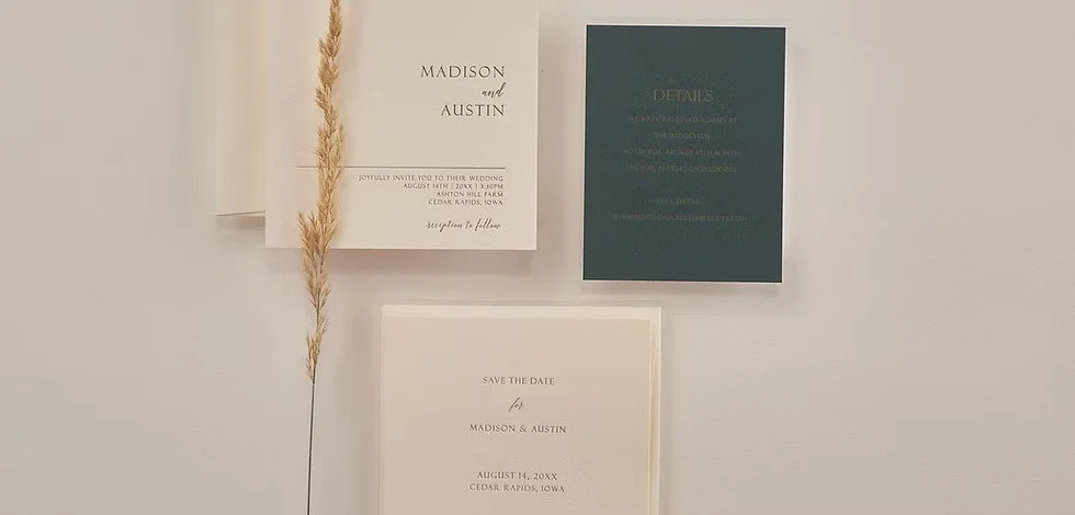 Wedding invitation cards and a green information card on a wall, with dried wheat stalk as decoration.