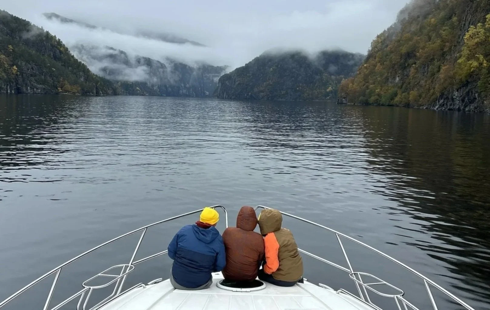 Three people sitting together on a boat surrounded by calm fjords, representing connection, emotional support, and healthy relationships.