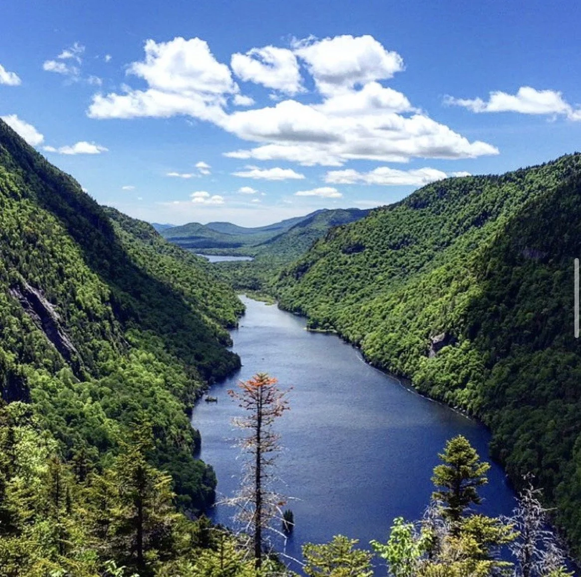 Adirondack mountain lake surrounded by forested peaks in upstate New York, where Lora Grieco was born and raised.