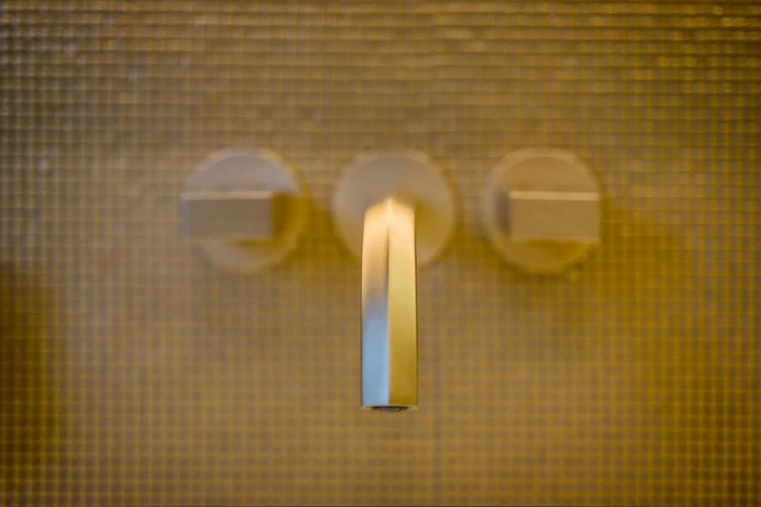 Nahaufnahme eines Goldknopfs in einer vertikalen Position auf einer goldfarbenen, texturierten Oberfläche.