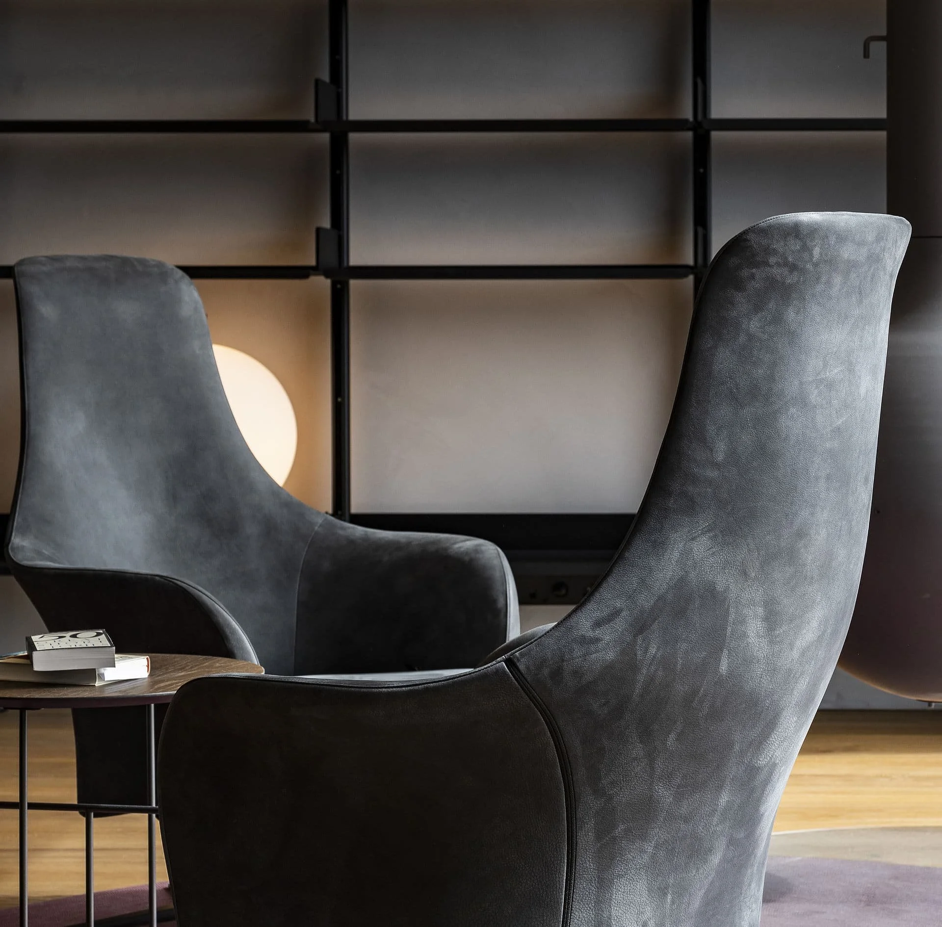 Ein modernes Wohnzimmer mit schwarzen Stühlen, einem kleinen Tisch mit Büchern und einem Hintergrundregal.