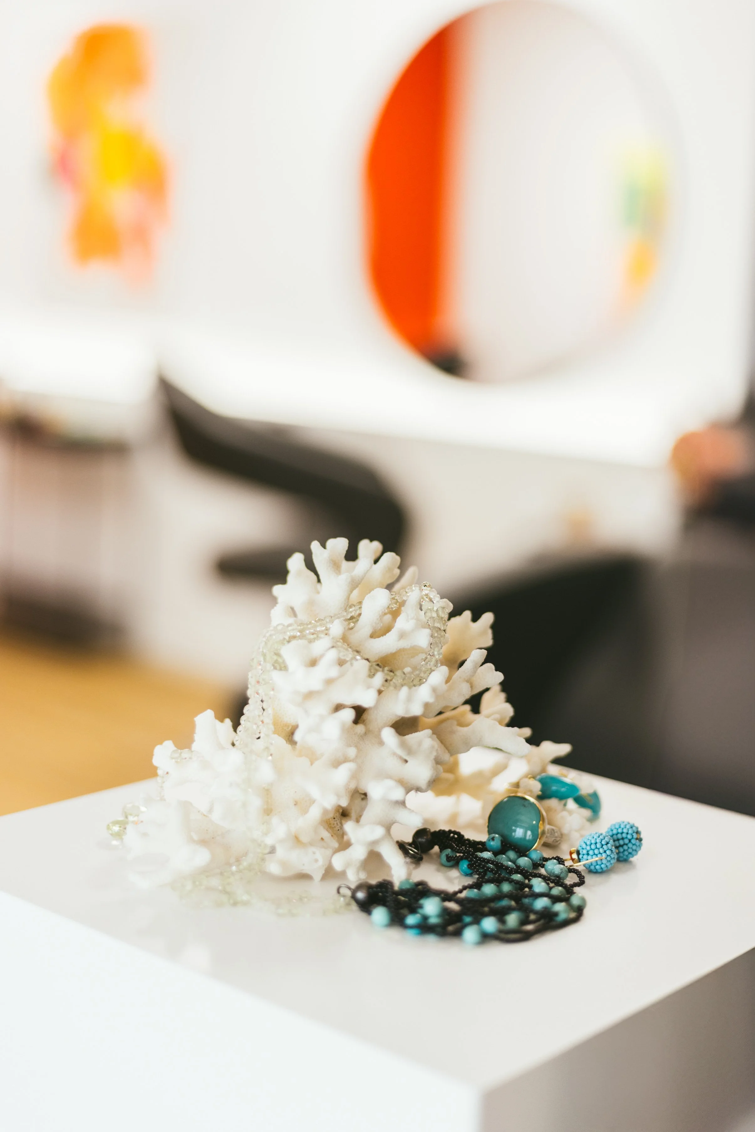 Schmuck, darunter eine weiße Korallen-Kunstdekoration, auf einem weißen Teller