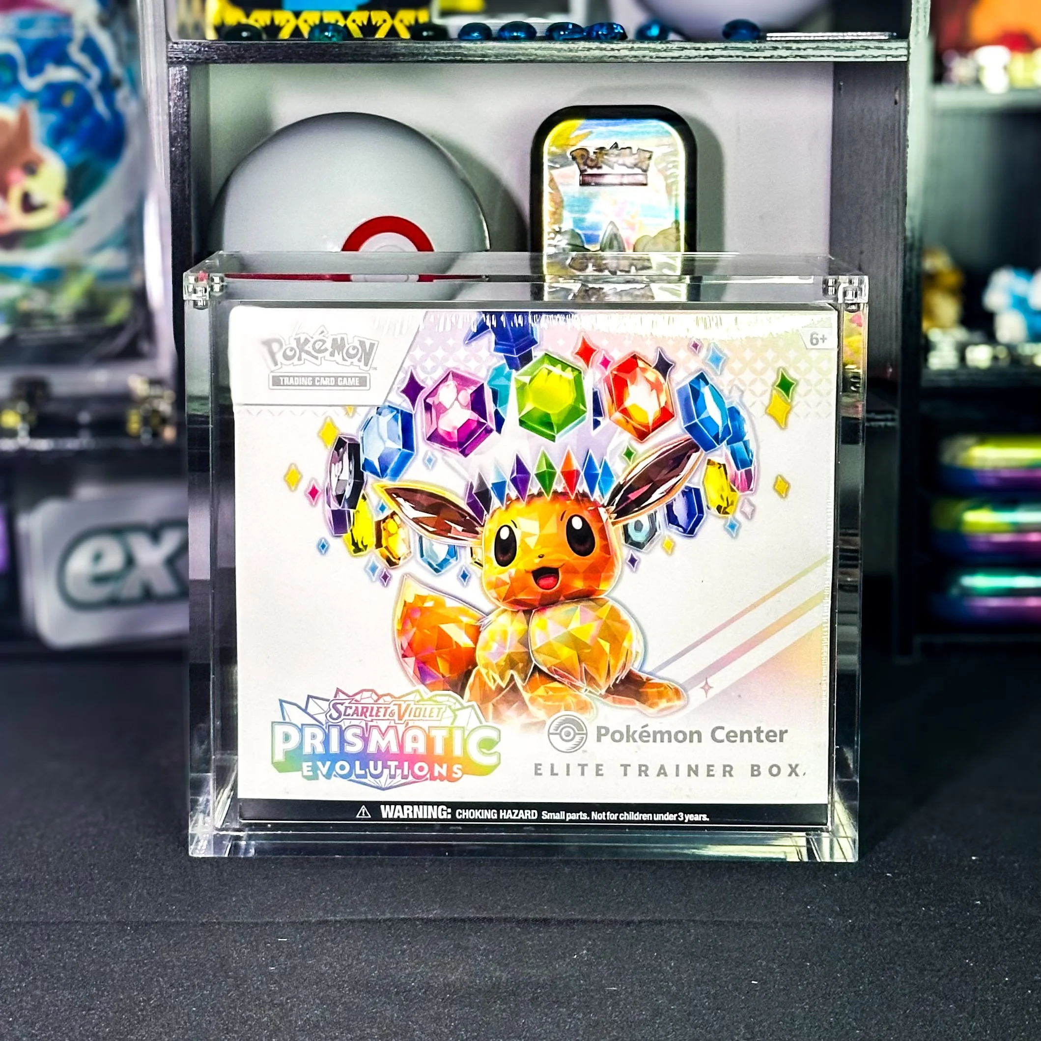 Pokémon Prismatic Evolutions Elite Trainer Box featuring a shiny Eevee with colorful, gem-like crystals and jewels in the background.